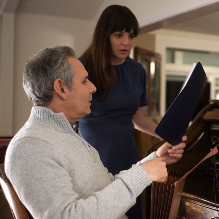 A man and woman sort through documents at a desk to locate a loved one's life insurance policy.